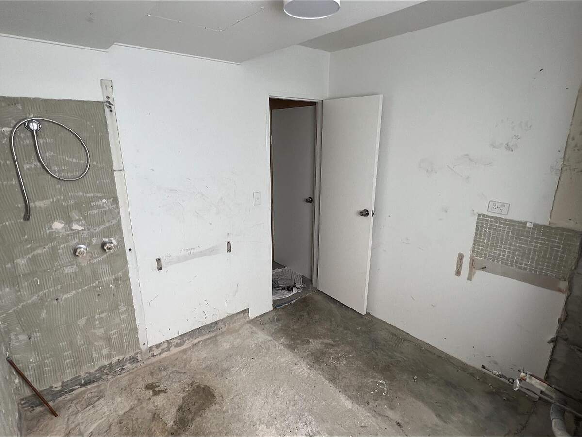 The same Manly bathroom after the strip-out: fixtures, tiles and linings removed down to the walls and concrete floor